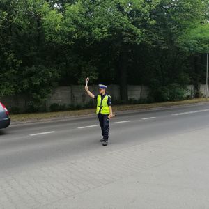 na zdjęciu policjant ruchu drogowego daje sygnał tarczą