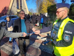 na zdjęciu policjant wręcza odblaski