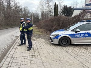 na zdjęciu policjanci stoją na drodze obok radiowozu