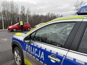 na zdjęciu radiowóz i policjant, który sprawdza stan trzeźwości kierujacego