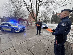 na zdjęciu policjanci z odblaskami przy radiowozach