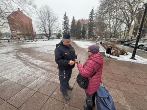 na zdjęciu policjant wręcza pieszemu odblask