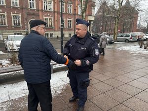 na zdjęciu policjant wręcza pieszemu odblask