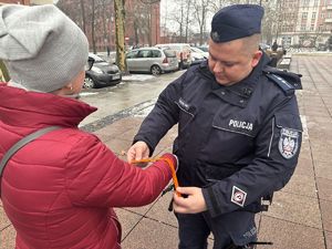 na zdjęciu policjant wręcza pieszemu odblask