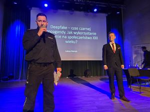 na zdjęciu policjant na scenie z prelegentem Łukaszem Pietrzykiem