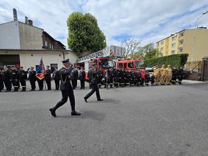 na zdjęciu komendanci przechodzą obok szyku strażaków