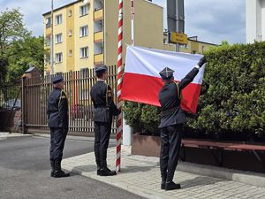 na zdjęciu strażacy umieszczają flagę na maszcie