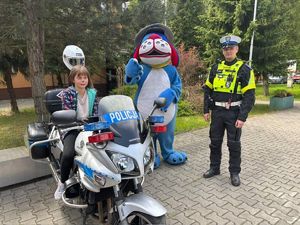 na zdjęciu policjant, Sznupek i dziecko na motocyklu