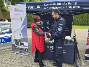 na zdjęciu policjant wręcza opaskę odblaskową