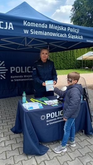 na zdjęciu policjantka wręcza dziecku książeczkę