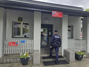 na zdjęciu policjant wchodzi do lokalu wyborczego