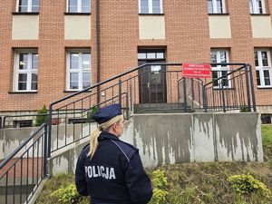 na zdjęciu policjantka stoi przed lokalem wyborczym