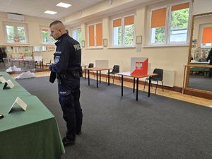 na zdjęciu policjant wewnątrz lokalu wyborczego