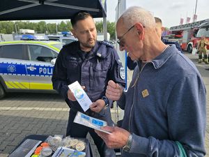 na zdjęciu policjant wręcza ulotki męzczyźnie