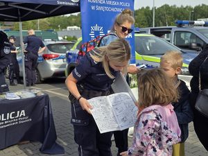 na zdjęciu policjantka wręcza dziewczynce kolorowankę