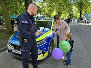 na zdjęciu policjant i dziecko z balonami