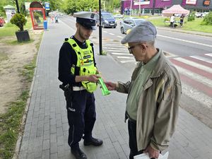 na zdjęciu policjant wręcza opaskę odblaskową