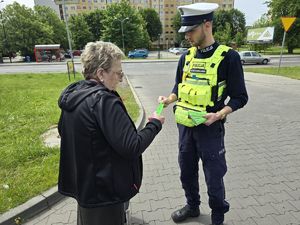 na zdjęciu policjant wręcza opaskę odblaskową