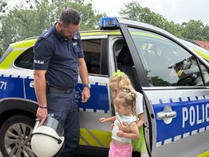 na zdjęciu policjant z dziewczynkami przy radiowozie
