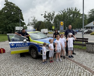 na zdjęciu policjanci z dziećmi przy radiowozie