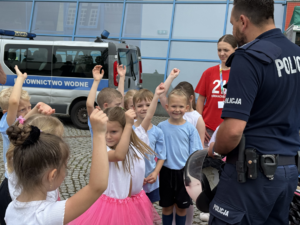 na zdjęciu policjant z dziećmi przy radiowozie