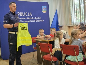 na zdjęciu policjant trzyma kamizelkę