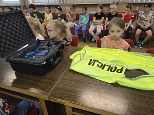 na zdjęciu dzieci oglądają kamizelkę Policja i miernik prędkości