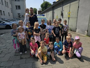 na zdjęciu zdjęcie grupowe policjanta i dzieci przy radiowozie