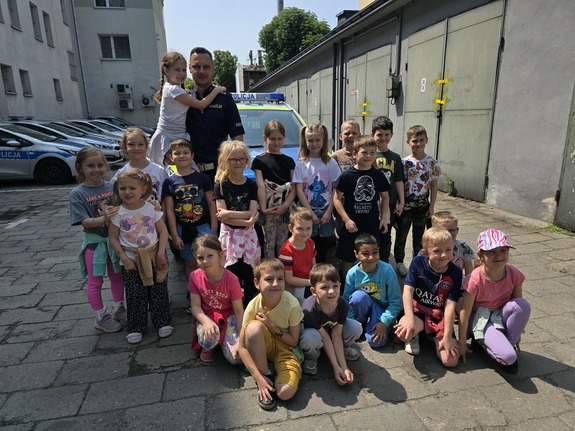 na zdjęciu zdjęcie grupowe policjanta i dzieci przy radiowozie