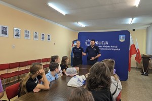 na zdjęciu policjantka i policjant rozmawiają z dziećmi