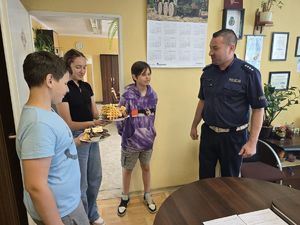 na zdjęciu naczelnik ruchu drogowego, któremu dzieci dają ciasta
