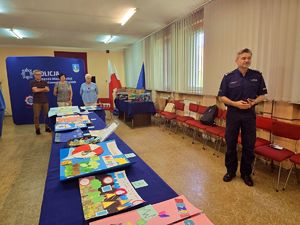 na zdjęciu komendant obok prac plastycznych