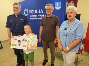 na zdjeciu zdjęcie grupowe z chłopczykiem i jego pracą