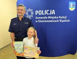 na zdjęciu komendant z dziewczynką, która trzyma dyplom