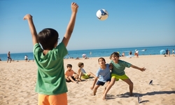 na zdjęciu dzieci grające w piłkę na plaży