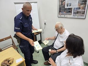 na zdjęciu policjant rozdaje ulotki