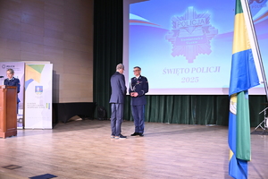 na zdjęciu przedstawiciel sejmiku wręcza komendantowi odznaczenie