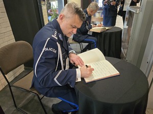 na zdjęciu insp. Wierzycki wpisuje się do księgi gości