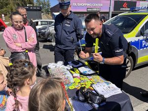 na zdjęciu policjant daje dziecku opaskę odblaskową