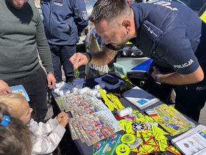 na zdjeciu policjant daje dziecku brelok odblaskowy
