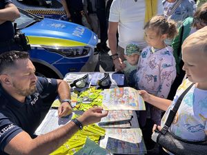 na zdjeciu policjant daje dziecku książeczkę
