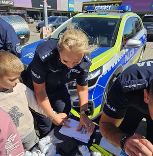 na zdjęciu policjantka robi chłopczykowi odcisk linii papilarnych