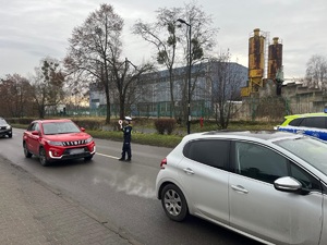 Na zdjęciu widnieje policjantka, która zatrzymuje nadjeżdżający samochód