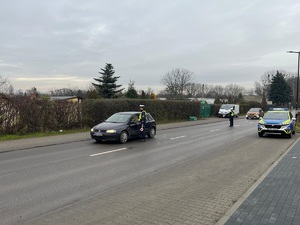 Na zdjęciu widać policjanta, który przeprowadza badanie trzeźwości na kierującym samochodem osobowym