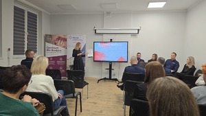 Zdjęcie przedstawia siedzących uczestników debaty oraz w drugim tle mówcę - kurator zawodową