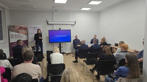 Zdjęcie przedstawia siedzących uczestników debaty oraz w drugim tle mówcę - kierownik Miejskiego Ośrodka Pomocy Społecznej w Siemianowicach Śląskich