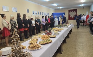 Na zdjęciu widać w pierwszym planie stół, który zastawiony jest potrawami, a w jego tle widoczni są pracownicy cywilni komendy wraz z komendantami