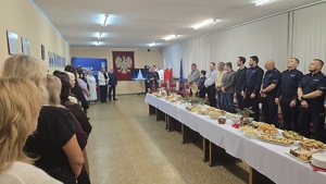 Na zdjęciu widać w pierwszym planie stół, który zastawiony jest potrawami, a w jego tle widoczni są pracownicy cywilni komendy wraz z komendantami