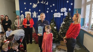 Zdjęcie przedstawia Komendanta Miejskiego Policji w Siemianowicach Śląskich wraz z dziewczynką, która wręczyła życzenia z okazji urodzin.