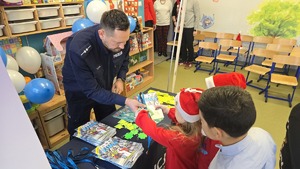 Na zdjęciu widać policjanta, który wręcza dziecku materiały profilaktyczne